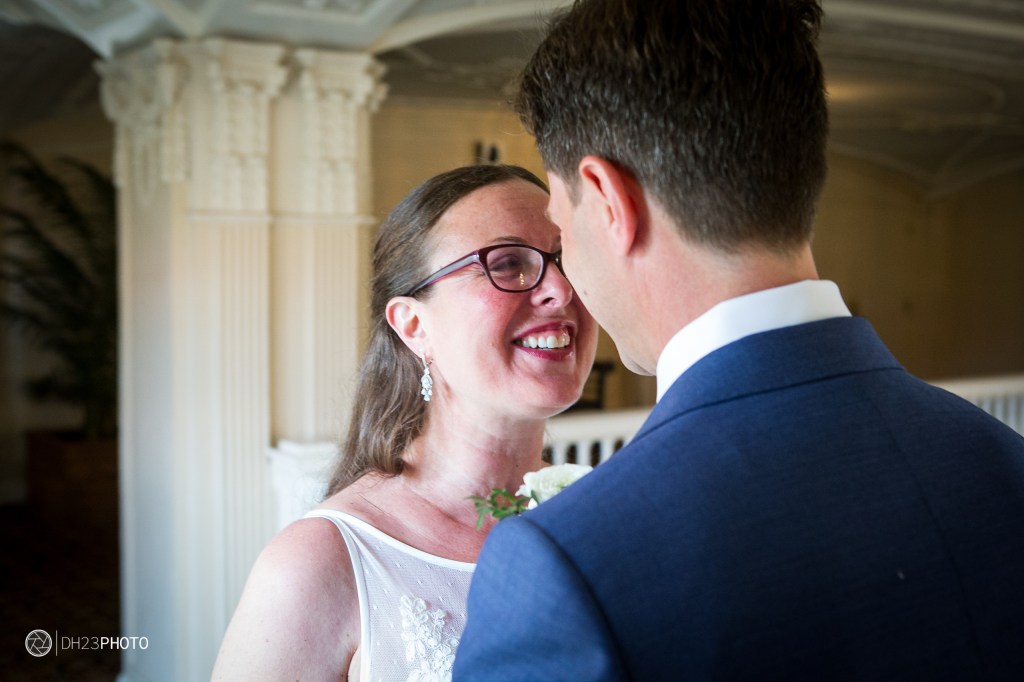 A joyful couple sharing an intimate moment, smiling at each other during a wedding ceremony in a beautifully decorated venue.