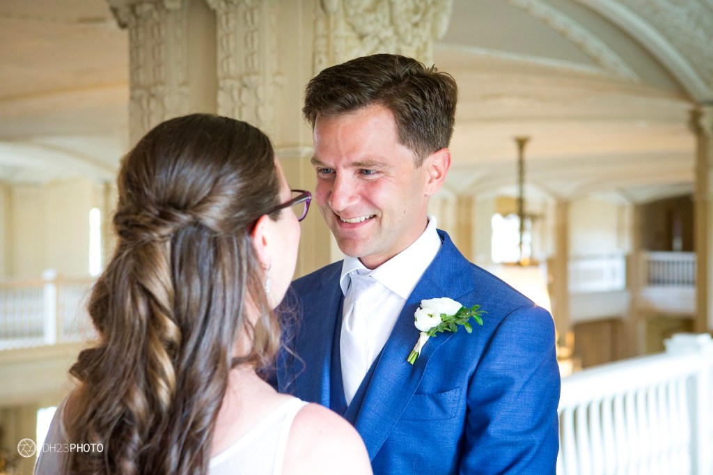 A happy couple exchanging smiles during a wedding ceremony in a beautifully decorated indoor venue.