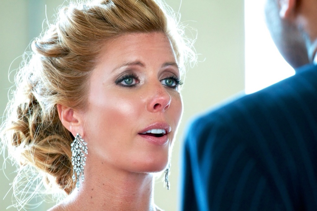 Close-up of a woman with styled hair and earrings, looking intently at someone off-camera.